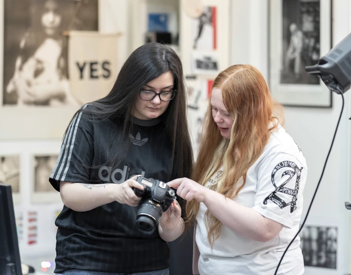 Two students reviewing photos on a DSLR camera in a creative photography studio. Two students reviewing photos on a DSLR camera in a creative photography studio.